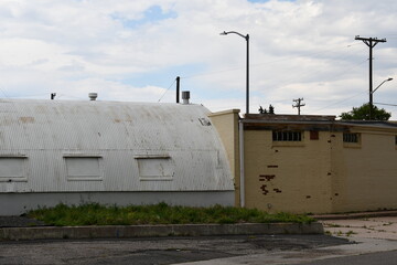 Abandoned buildings and alleyway. Overgrown grass.