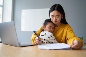 Working Mom Comforting Sleeping Child at Desk - Home Office Lifestyle