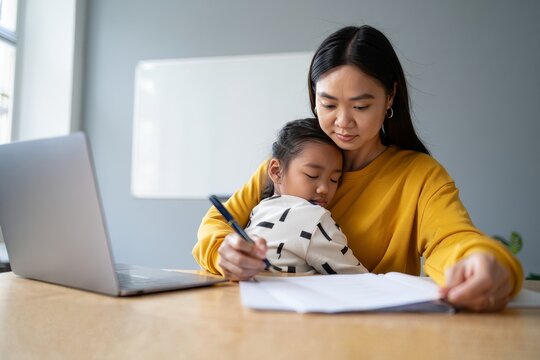 Working Mom Comforting Sleeping Child at Desk - Home Office Lifestyle