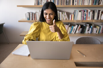Satisfied Indian woman giving positive feedback, showing thumb-up gesture at virtual meeting using...
