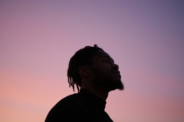 Silhouette of Young Man Looking Up at Sunset Sky