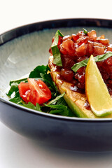 A Vibrant Dish Featuring Slice of Avocado Topped with Fresh Tomato Salsa, Lime Wedge, and Basil Leaves on a Bed of Greens in an Elegant Bowl