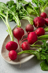 bunch of radishes with green leaves on grey background with copy space
