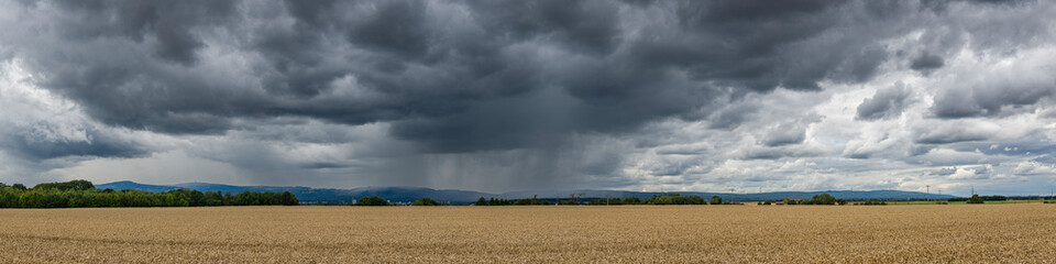 Panoramansicht eines über das Land ziehenden Unwetters mit Starkregen und grauer-schwarzer...