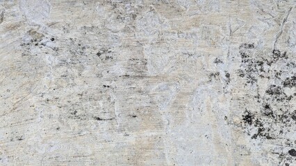 A mottled, weathered grey concrete surface with dark stains and textures, ideal for a grunge or...