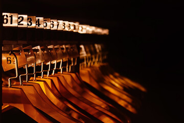 Wooden hangers with numbers in dark cloakroom. Copy space