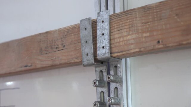 Temporary door closure: a wooden beam is secured with metal brackets and guide rails. Used during renovation or construction phases.