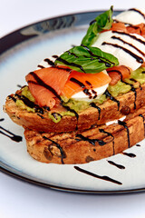 A Delicious Avocado Toast Topped with Fresh Salmon, Creamy Mozzarella, and Drizzled with Balsamic Reduction on a Rustic Plate