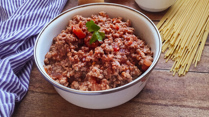 ground beef bolognese in a white bowl with a wooden bottom