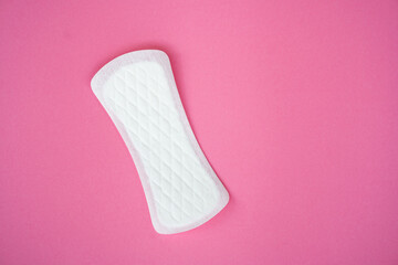A single white sanitary pad isolated on a plain pink background. Suitable for topics related to...