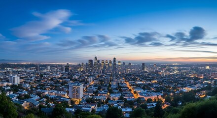 Naklejka premium Urban cityscape at twilight with illuminated skyscrapers and a vibrant blue sky