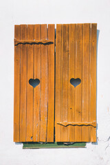 Wooden shutters on rustic style windows with a heart-shaped neckline