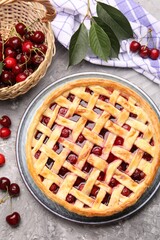 Tasty cherry pie and berries on grey textured table, flat lay