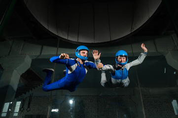 A male instructor teaches a woman how to fly in a wind tunnel. Free fall simulator.