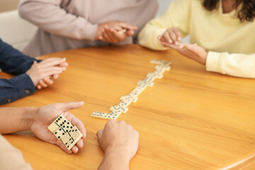 Friends playing dominoes at wooden table, closeup