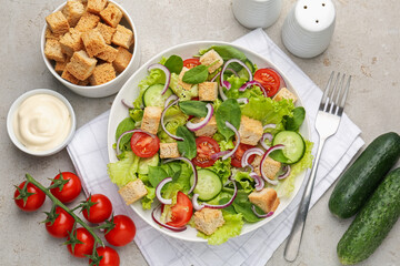 Delicious salad with croutons and vegetables served on light grey table, flat lay