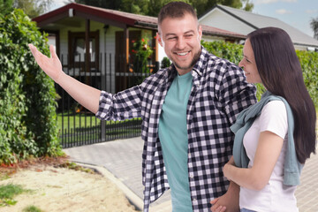 Happy couple near their house outdoors. Real estate ownership