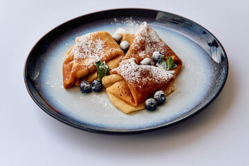 Deliciously Crafted Crepes Served with Fresh Blueberries and Mint on a Beautiful Plate for an Irresistible Treat