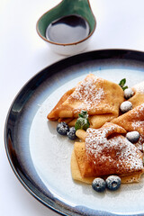 Delicious Crepes Served with Blueberries and Maple Syrup on a Stylish Plate for an Appealing...