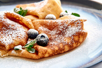Deliciously Fluffy Crepes Topped with Fresh Blueberries and Sprinkled with Powdered Sugar for an Irresistible Breakfast Treat