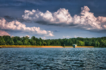 A nice landscape of cool blue water by the dam area at Lake Wheeler Park in Raleigh, North Carolina USA under a cloudy blue sky.