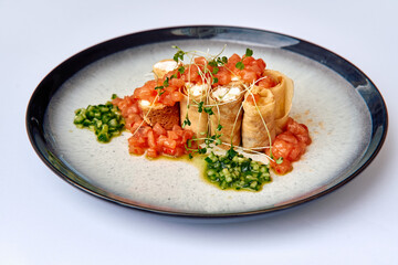 Delicately Plated Gourmet Dish Featuring Crispy Rolls Filled with Cheese, Topped with Fresh Tomato...