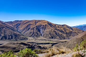 Expansive landscape showcasing a serpentine road amidst majestic Andean mountains under a clear blue skyExpansive landscape showcasing a serpentine road amidst majestic Andean mountains under a clear 