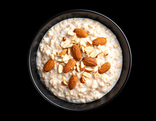 A bowl of oatmeal with almond nut topping. Isolated on a black background.