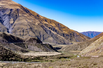 Expansive arid mountain valley featuring a parched riverbed and rugged terrain in Salta, Argentina.