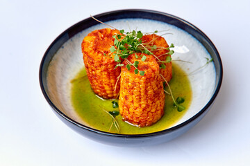 A Servings of Deliciously Grilled Corn Fritters Garnished with Fresh Microgreens and Drizzled with Vibrant Green Sauce Served in a Bowl