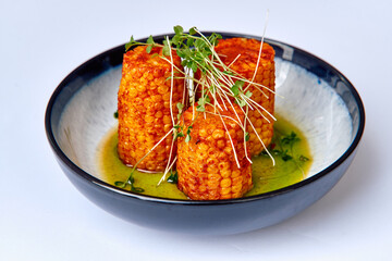 A Vibrant Dish Featuring Towering Grilled Corn Cylinders Garnished with Fresh Greens in a Flavorful Herb Sauce