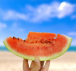 hand holds waterlemon on the beach, beach background, summer background, fruits 