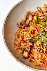 A Colorful Plate of Octopus Fried Rice Garnished with Fresh Vegetables, Green Onions, and Sesame Seeds for a Flavorful Culinary Experience
