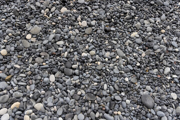 Close up view of smooth black pebbles at black sand beach in Iceland for background use.
