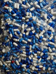 Assorted white, blue, and multicolored pills in blister packs arranged in a pile, representing modern healthcare, medicine, treatment, pharmaceutical products, and medical supply concepts

