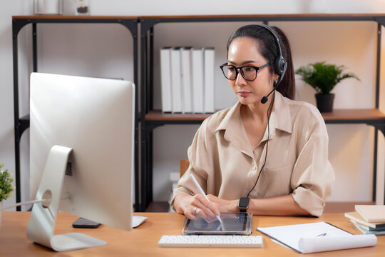 Professional young asian business woman working and meeting online while writing on tablet in modern home office, businesswoman video call with conference distant, call center and support.