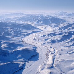 Aerial view of a snowy river winding through a mountain range