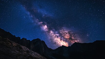 A close-up of the Milky Way stretching across the night sky above a quiet mountain.