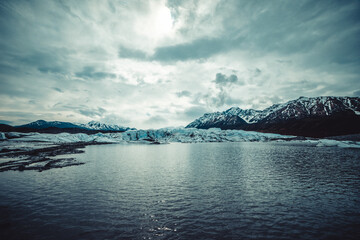 Glacial Lake with Snowy Mountains Under Cloudy Sky
