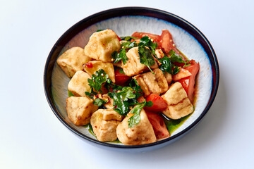A Colorful Dish Featuring Pieces of Tofu Nestled Among Fresh Tomatoes and Vibrant Cilantro,...