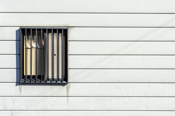 iron-barred windows on white wooden plank walls
