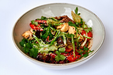A vibrant bowl of fresh salad featuring a medley of greens, juicy tomatoes, mushrooms, and aromatic herbs, garnished with sesame seeds for added flavor.