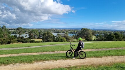 Young man on a bmx bike in a park taking in the view