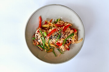 A colorful bowl of mixed stir-fried noodles featuring vibrant vegetables and a sprinkle of sesame seeds for a delightful meal experience