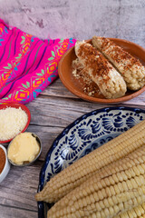 A table served with corn on the cob to prepare Mexican food with mayonnaise, cheese, and chili...
