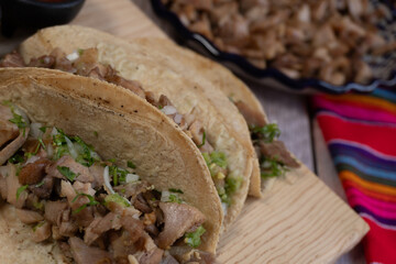 Close-up of a plate with several prepared carnitas tacos in the background. A plate with pork carnitas, Mexican food.