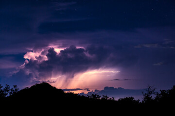 稲光に照らされる雷雲と山のシルエット