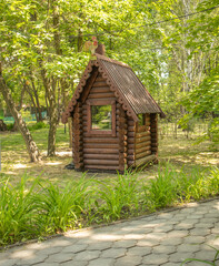 Vintage installation in the park. A small log fairy-tale house, vertical.