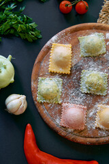 Freshly Made Ravioli with Colorful Fillings Surrounded by Fresh Vegetables and Herbs on a Rustic...