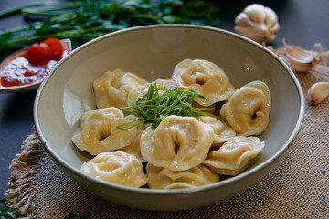 A Delicious Serving of Homemade Dumplings Garnished with Fresh Herbs and Accompanied by Spicy Sauce on a Rustic Table Setting